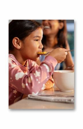 Cute little girl enjoying breakfast with milk and corn flakes