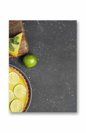 Plate and wooden board with tasty lime tart on black background