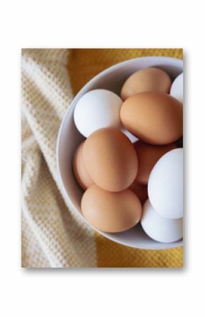 Brown and white eggs in a white bowl overhead photo