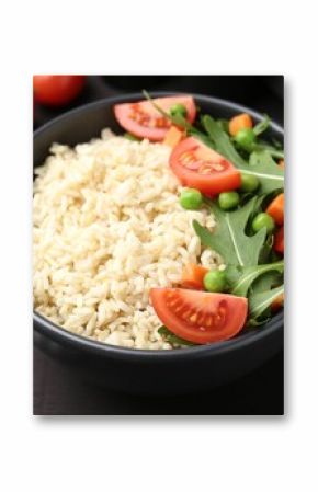 Delicious brown rice with vegetables on black wooden table, closeup