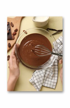 Female hands whisking melted chocolate on beige background. Top view