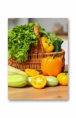 Wicker basket with different fresh vegetables on wooden kitchen counter