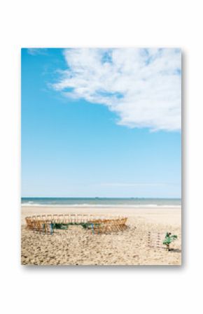 Circle of wooden folding chairs on the beach for a wedding ceremony with sea view