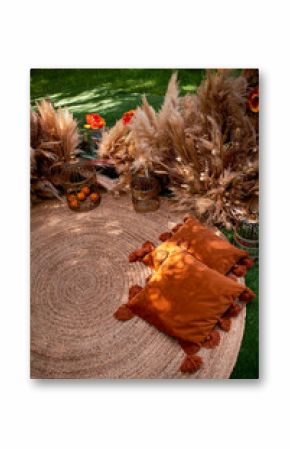 Orange pillows with tassels in nature. Boho style, outdoor picnic.