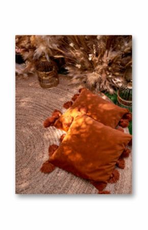 Orange pillows with tassels in nature. Boho style, outdoor picnic.