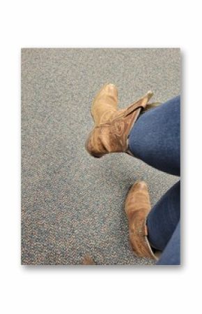 A person wearing stylish cowboy boots and blue jeans stands on a carpet