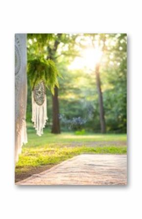 Bohemian ceremony space bathed in sunlight. Lush greenery and a dream catcher adorn the area