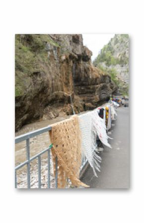 Colorful handwoven shawls and scarves displayed along a metal railing in the scenic Chegem Gorge, Kabardino-Balkaria, Russia