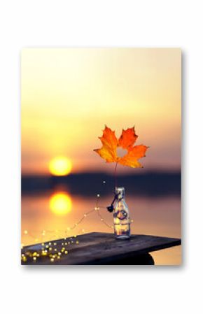 Autumn Glow: Glass Bottle with Colorful Leaf and Fairy Lights by the Sea