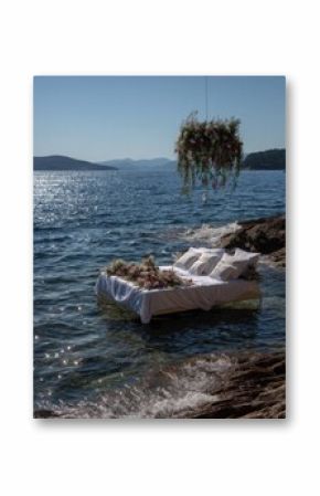 Floating bed on the water, adorned with flowers, overlooking a serene ocean vista