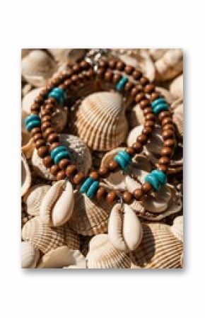 Handmade beaded necklace with cowrie shell charm on a bed of seashells.
