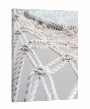 Close-up of a handmade macrame wall hanging. The intricate knots and patterns are visible, showcasing the craftsmanship and texture of the natural fibers. 