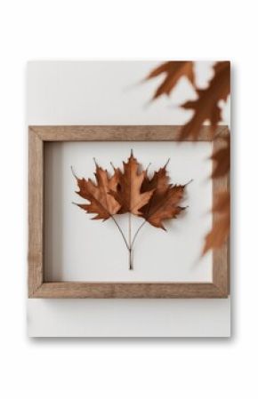 Artistic arrangement of autumn leaves in wooden frame.