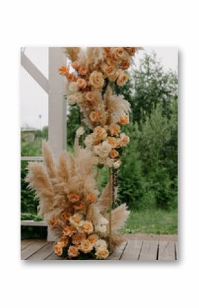 A beautifully crafted wooden deck is adorned with an array of vibrant flowers and elegant pampas grass, creating a stunning setting for a wedding ceremony