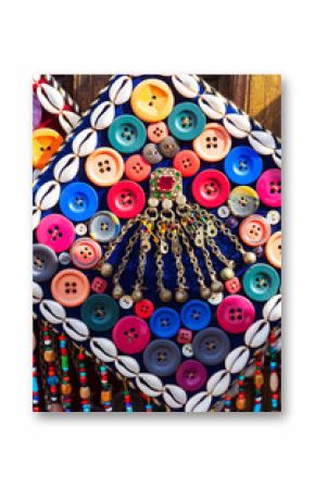 A decorative pano crafted from buttons and shells, is hanging on a wall