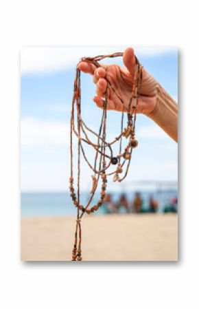 Hand holding artisanal beaded necklaces on the beach