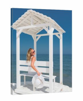 Beautiful young lady relaxing on small pavilion on the beach