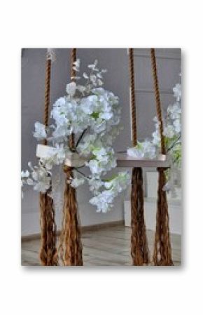 Decorative flower swing with white blooms and braided rope in a serene indoor setting
