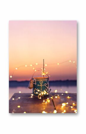 candle in a can as maritime lantern with sparkler and fairy lights in sunset