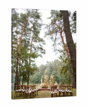 Forest wedding ceremony with dried flower arch and guest chairs set by the lakeside.