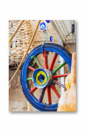 A vibrant and colorful wooden wheel adorned with ominous evil eyes hanging from it