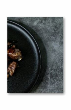Korean Galbi Jjim, braised short ribs with spring onion and pepper in black plate on dark background