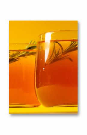 Glasses with drinks and thyme over yellow background