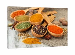 Assortment of spices in wooden spoons on wooden background