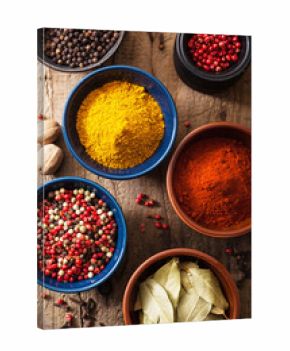 spices in bowls: pink black pepper, paprika powder, curry, bay l