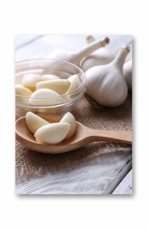 Fresh sliced garlic in glass bowl on wooden background