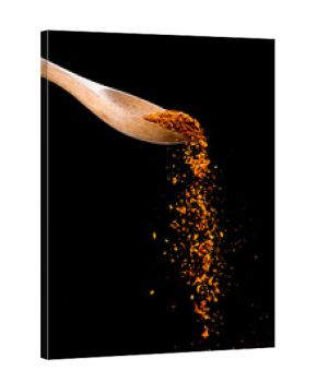 cayenne pepper shaker,wood spoon of cayenne pepper on black back