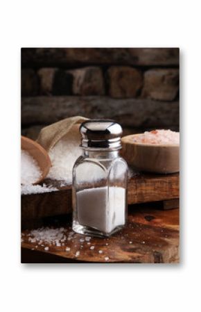 Salt Shaker and salt on wooden table.