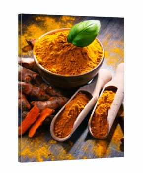 Composition with bowl of turmeric powder on wooden table
