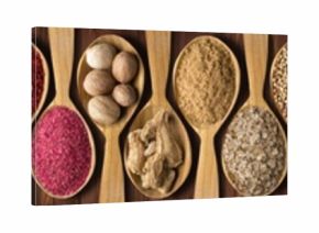 spices in wooden spoons on black table. set of condiments and herbs for decorating website headers or packs with food.