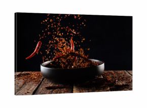 Pouring cayenne pepper powder into the bowl on wood table,Motion blur