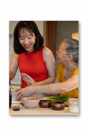 Asian family cooking ramen in modern kitchen with soy sauce and sliced vegetables