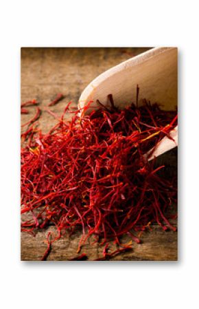 saffron threads with spice shovel on wooden background