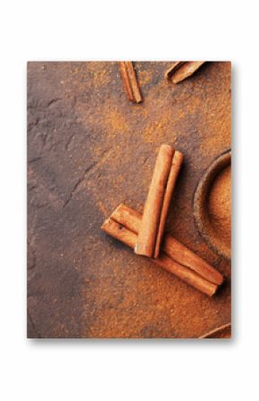 Heap of cinnamon sticks and powder on brown rustic background top view. Aromatic spices.