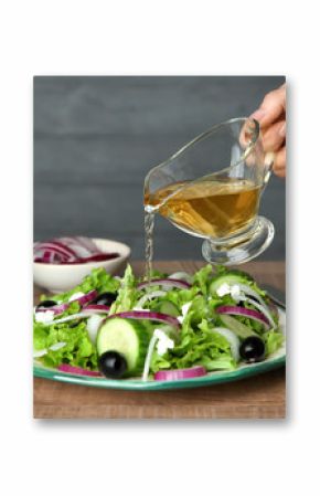 Woman adding tasty apple vinegar to salad with vegetables on table