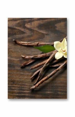 Dried vanilla pods and flower on wooden background