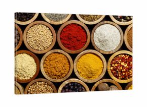Background of arranged spices in small wood bowls from above.