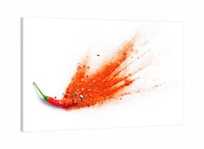 Chili powder and flakes burst out from red chili pepper