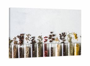Various dry spices in glass tubes and spilled on gray background. Copy space. top view