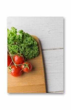 Tomatoes and parsley on chopping board over wooden floor
