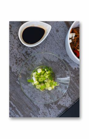 Delicious noodle dish with soy sauce and fresh green onions on table, at home