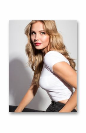 Awesome caucasian attractive sexy professional female model with blond hair posing in studio wearing white shirt and black ripped jeans, smiling, isolated on white background