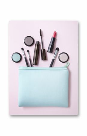 Aerial view of a make up bag with cosmetic products spilling out on to a pastel pink background