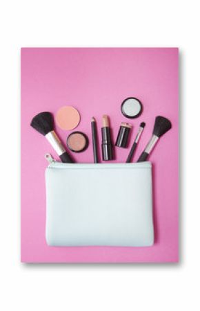 Aerial view of make up products spilling out of a blue cosmetics bag on to a bright pink background