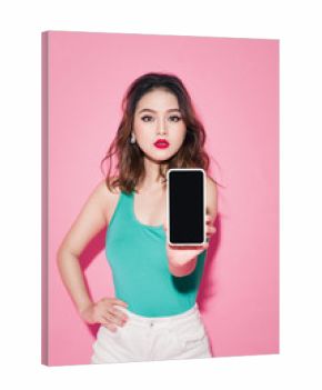 Asian girl with professional makeup showing smartphone screen on pink background.