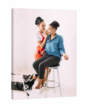 Professional make-up artist doing beautiful girl makeup in studio